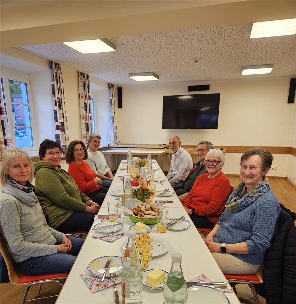 Eine Gruppe von Personen sitzt an einem Tisch und führt ein Gespräch.