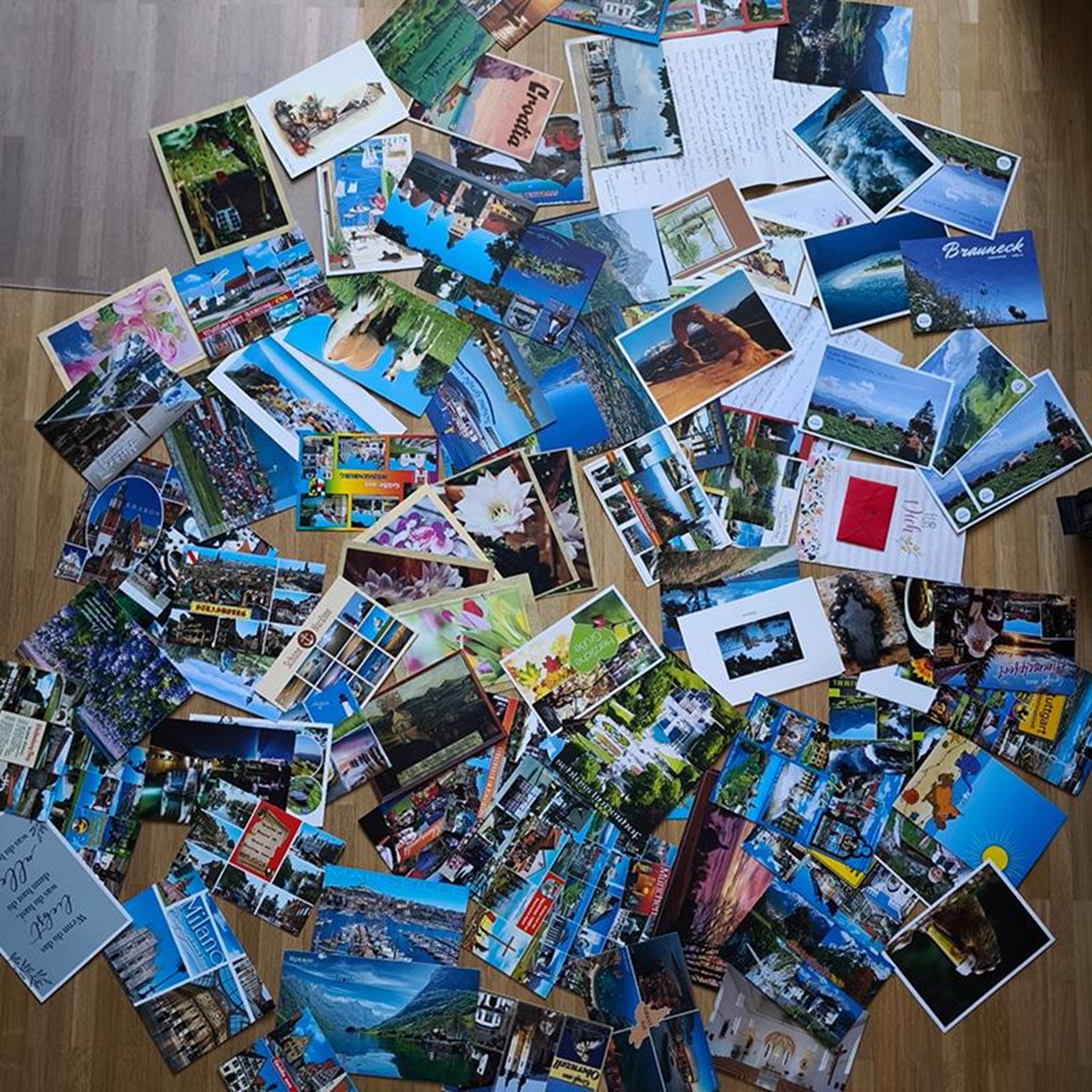 auf dem Bild sind viele Postkarten verstreut auf einem Holzboden zu sehen