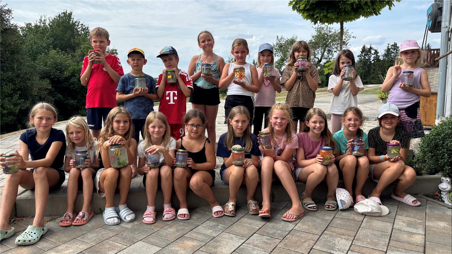Kinder beim Zeltlager der Pfarrcaritas Perach präsentieren ihre selbst gestalteten Aquarien in Gläsern.