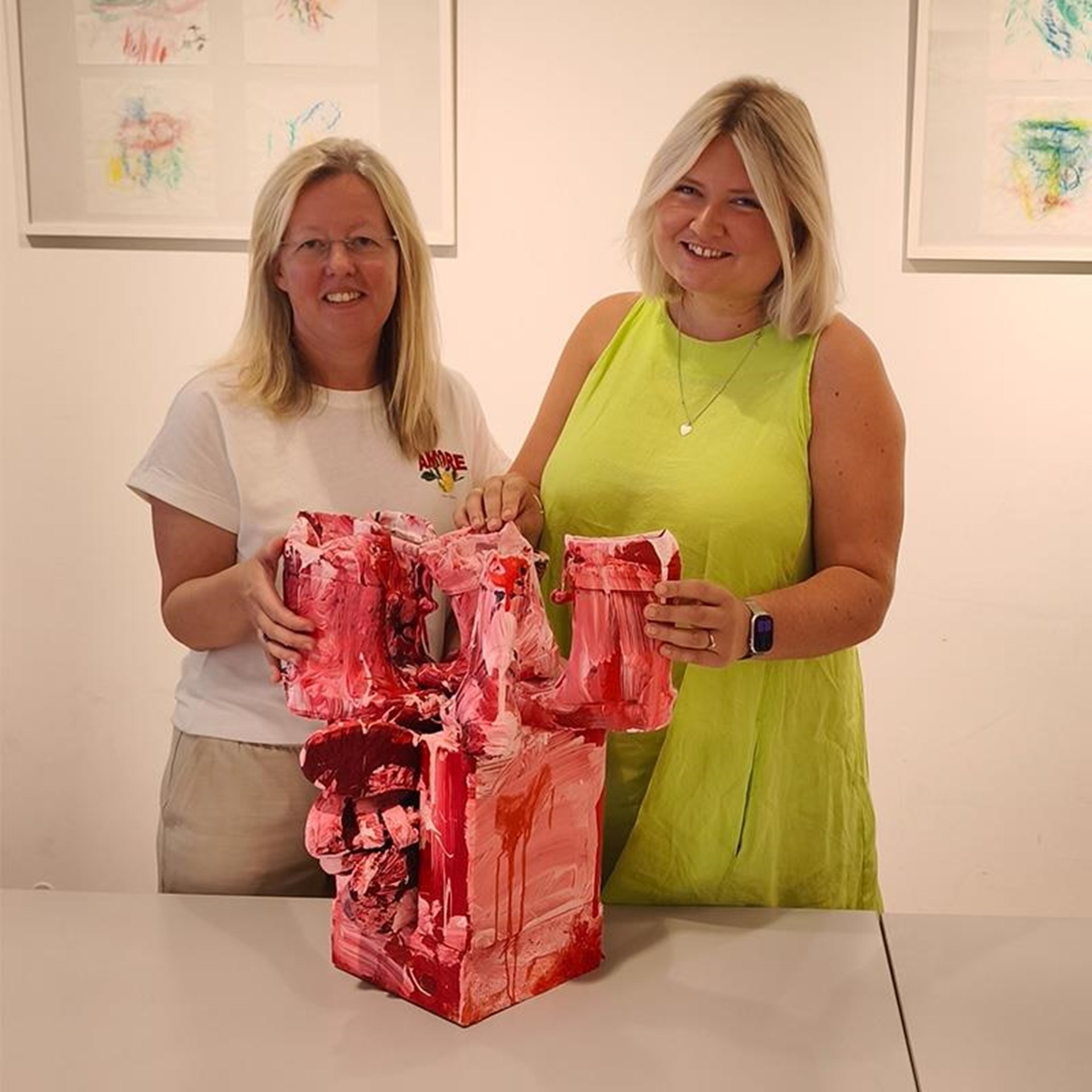 auf dem Bild sind zwei Frauen zu sehen welche ein Kunstwerk halten 