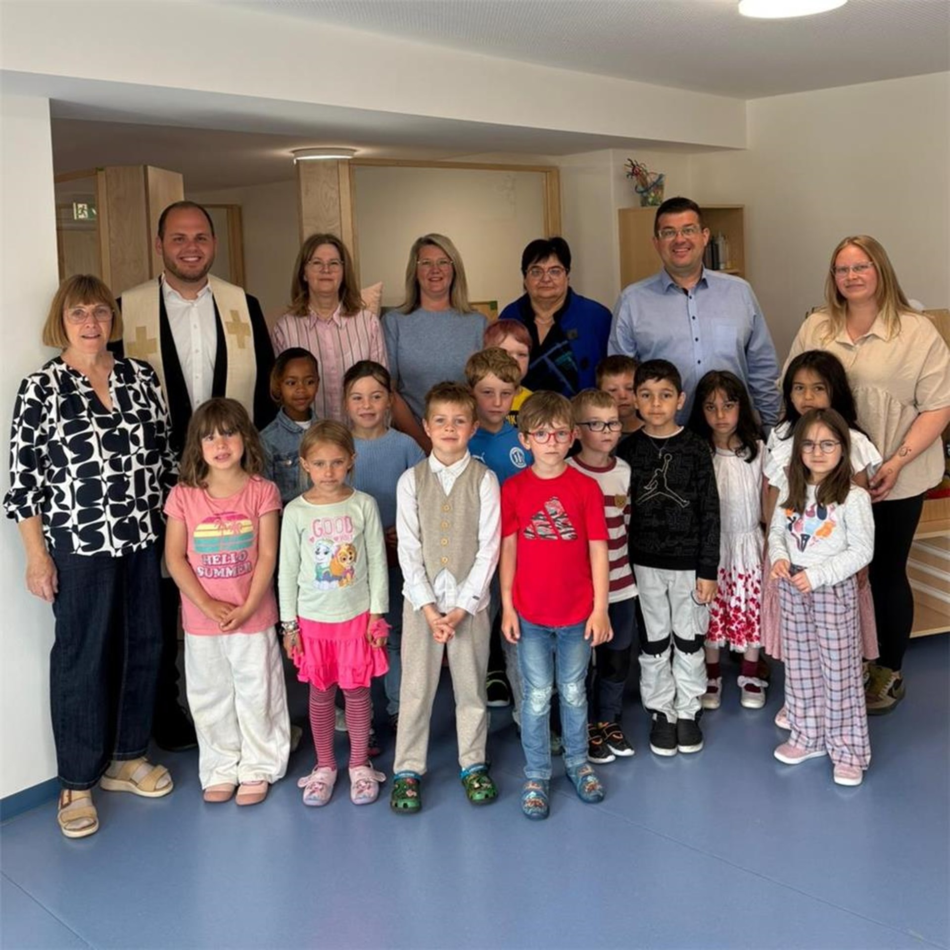 Kinder der Caritas Kita St. Josef Regen stehen gemeinsam mit Kita-Leitung, Pfarrer, Bürgermeister, Elternbeirat und weiteren Beteiligten in den neu eröffneten Räumen.
