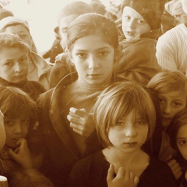 Älteres Foto von mit mehreren Kindern die durch eine Glastüre schauen 