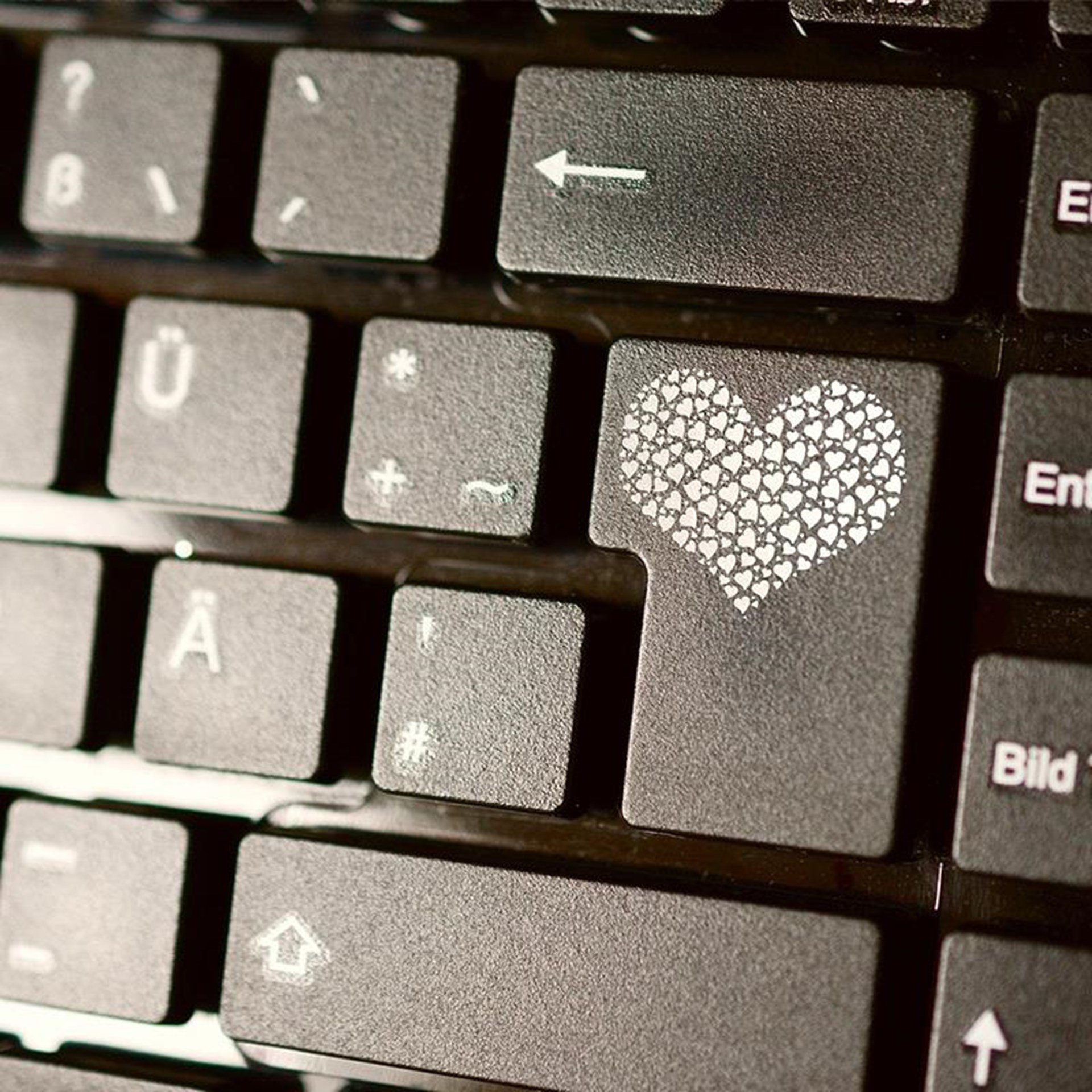Eine schwarze Tastatur mit weißen Buchstaben und einem gemalten weißen Herz auf der Enter Taste